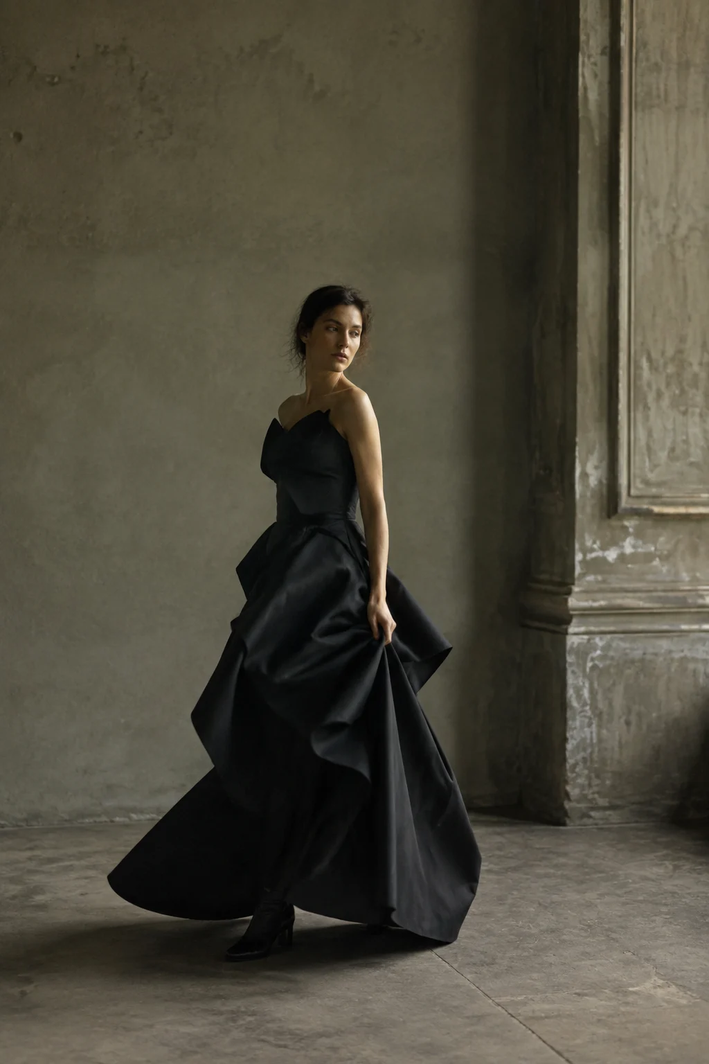 A woman in a sculptural black dress in an atelier